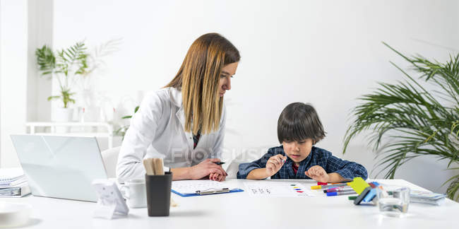 Junge färbt Formen mit bunten Stiften für entwicklungspsychologischen Test in Arztpraxis. — Stockfoto