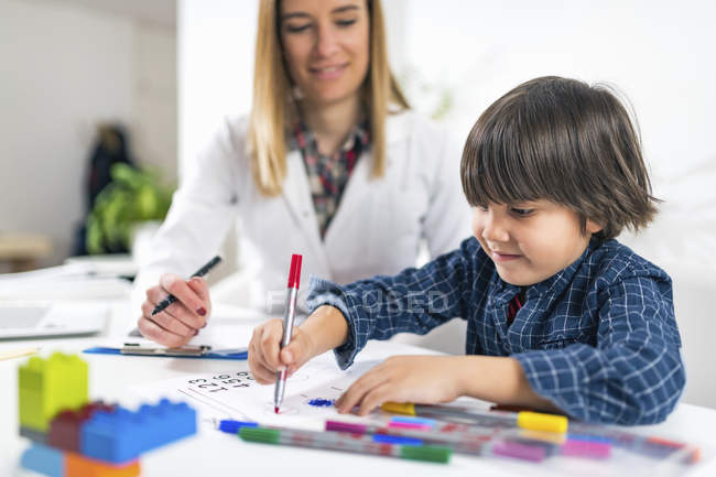 Preschooler boy coloring shapes with colorful pens for developmental psychology test in psychologist office. — Stock Photo