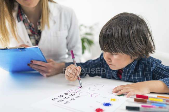 Мальчик раскрашивает фигуры красочными ручками для психологического теста на развитие в офисе психолога . — стоковое фото