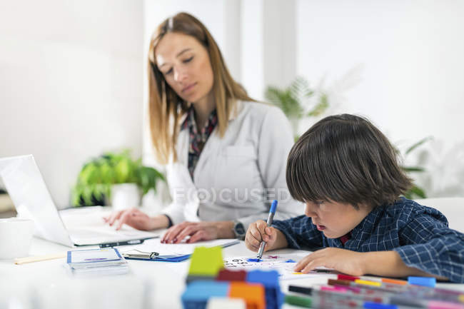 Junge färbt Formen mit bunten Kugelschreibern für entwicklungspsychologischen Test im Psychologenbüro. — Stockfoto