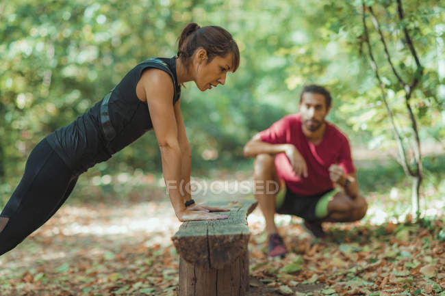 Mulher fazendo flexões no parque com personal trainer . — Fotografia de Stock