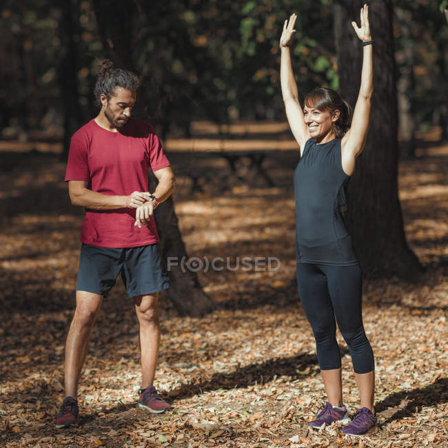 Young woman stretching after training with personal trainer in park. — Stock Photo