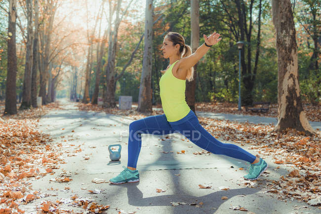 Mujer estirándose con los brazos extendidos en el parque de otoño . - foto de stock