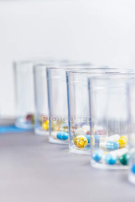 Variedade de pílulas farmacológicas em copos de plástico descartáveis, conceito de medicação . — Fotografia de Stock