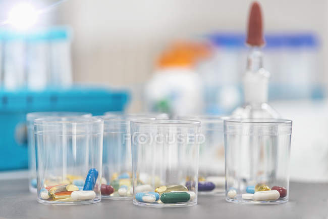 Variety of pharmacological pills in disposable plastic cups, medication concept. — Stock Photo
