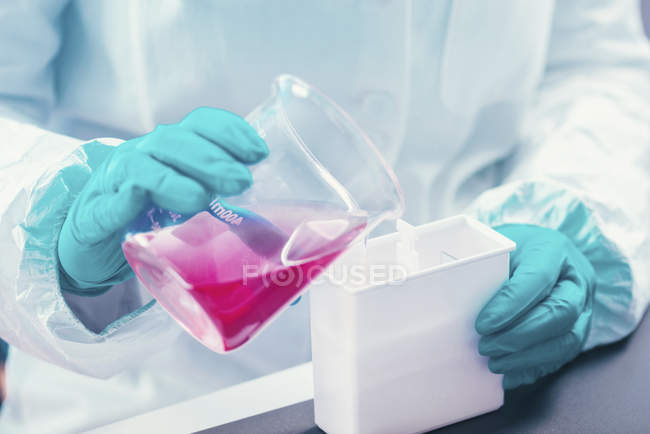 Mikrobiologie-Techniker gießt Flüssigkeit mit Bakterienstämmen in Plastikbox. — Stockfoto