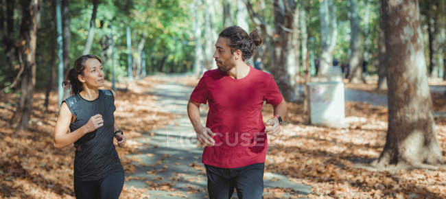 Donna e uomo che fanno jogging all'aperto nel parco autunnale . — Foto stock