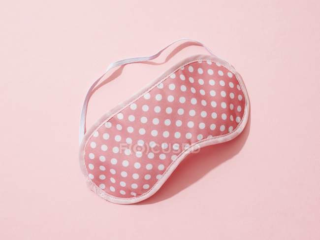Polka dots sleep mask on pink background. — Stock Photo