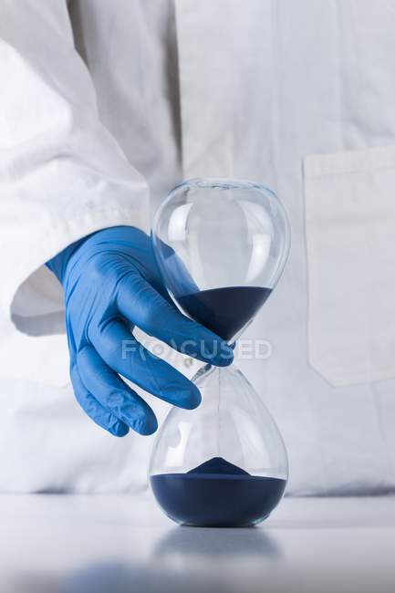 Hourglass in hand of scientist, conceptual image of passing time. — Stock Photo