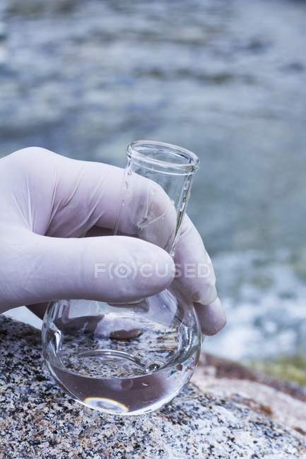 Scientist hand sampling water in flask for quality testing. — Stock Photo
