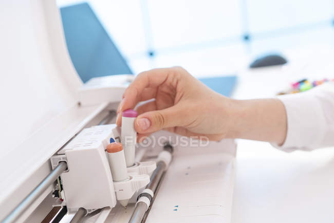 Hand of woman inserting paper and pens into plotter. — Stock Photo