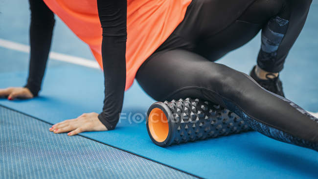 Primo piano di atleta femminile che si allunga con rullo di schiuma all'aperto . — Foto stock