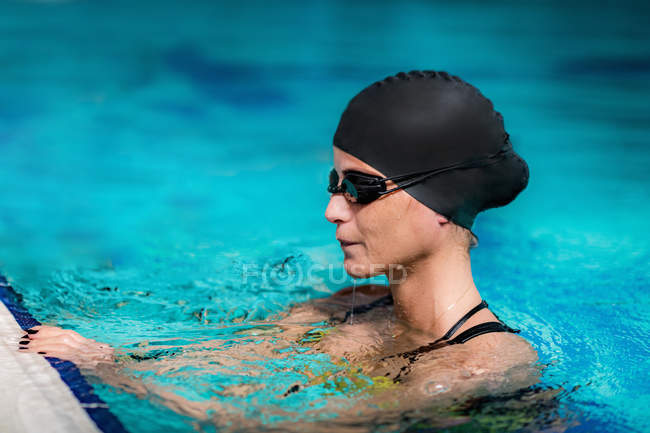 Woman resting after swimming at poolside of indoor pool. — Stock Photo