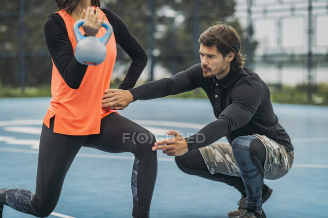 Молода спортивна жінка піднімає чайник як працює з персональним тренером фітнесу . — стокове фото