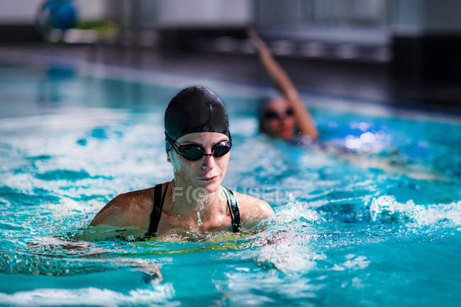 Junge Frauen schwimmen im Hallenbad-Wasser. — Stockfoto