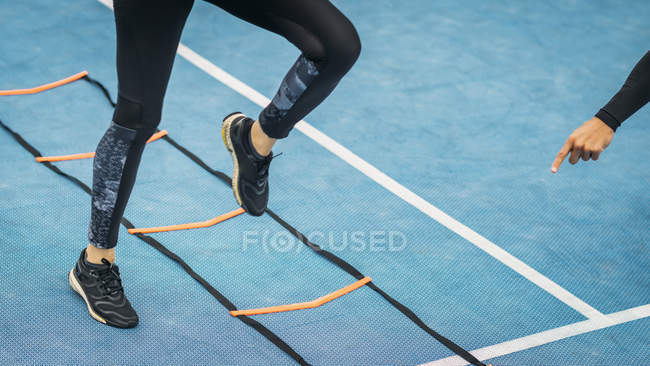 Beine der Frau beim Training mit persönlichem Fitnesstrainer mittels Agility-Leiter. — Stockfoto