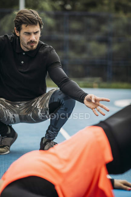 Cropped of sporty woman exercising outdoors with personal fitness trainer. — Stock Photo