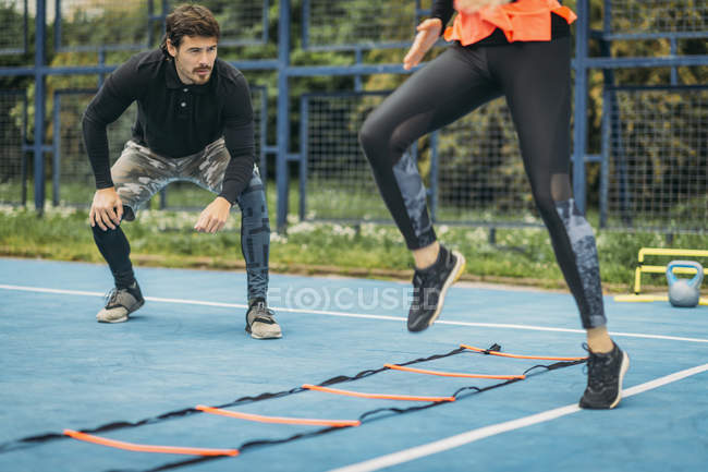 Woman exercising with personal fitness coach using agility ladder. — Stock Photo