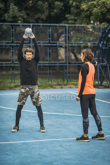 Fit and healthy personal trainer showing kettlebell exercise to female client. — Stock Photo