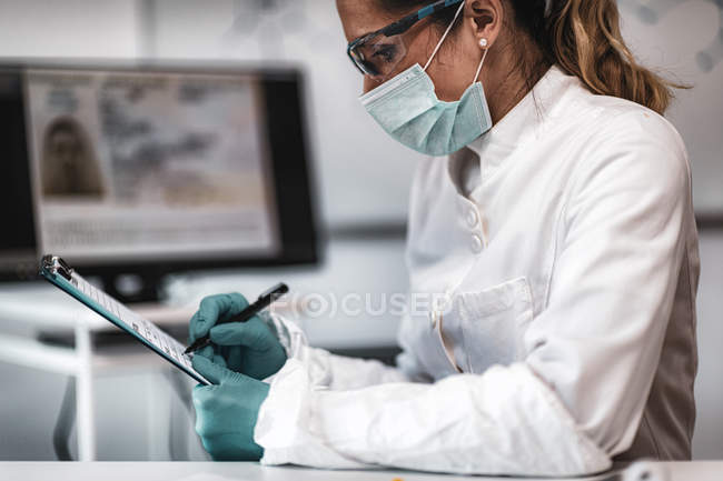 Police digital forensic science expert taking notes while investigation. — Stock Photo