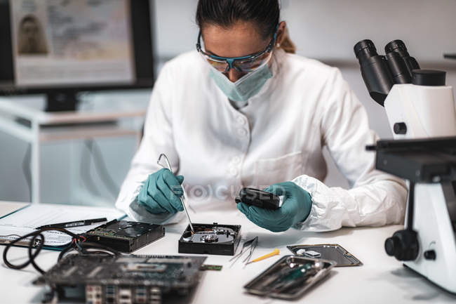 Experta forense digital femenina examinando disco duro de computadora con equipo electrónico en laboratorio de ciencia policial
. - foto de stock