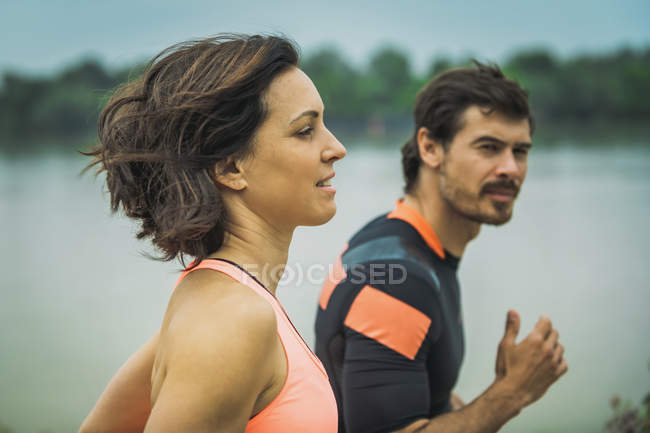 Mujer joven haciendo ejercicio corriendo maratón por el río con entrenador personal . - foto de stock