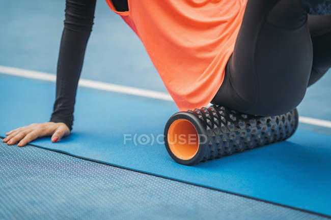 Female athlete stretching with foam roller outdoors on stadium. — Stock Photo