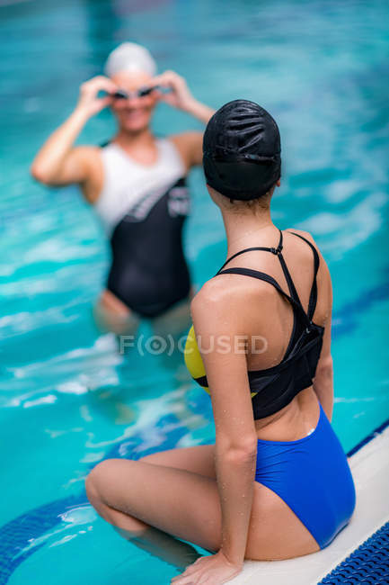 Nadadoras descansando junto a la piscina en piscina cubierta . - foto de stock