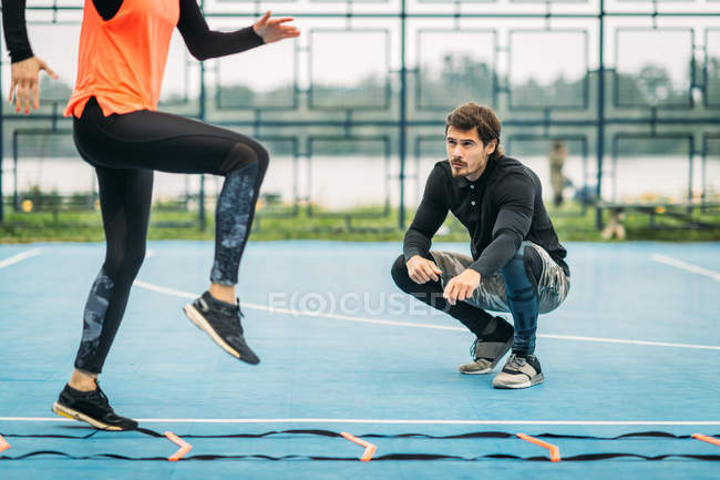 Young woman exercising with personal fitness coach using agility ladder. — Stock Photo