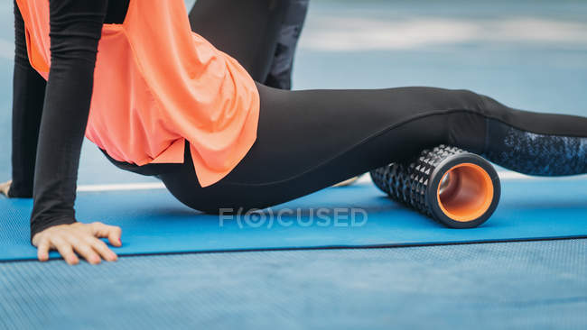 Close-up de atleta feminina alongamento com rolo de espuma ao ar livre no estádio
. — Fotografia de Stock
