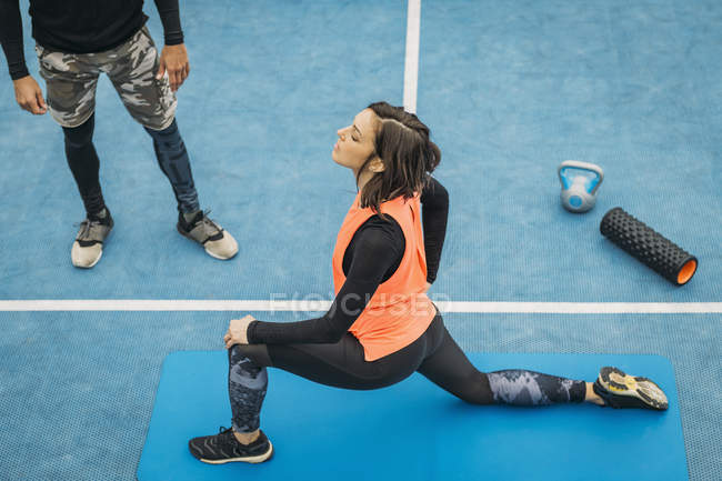 Подходит молодая женщина, делающая упражнения на растяжку после тренировки с личным фитнес-тренером . — стоковое фото