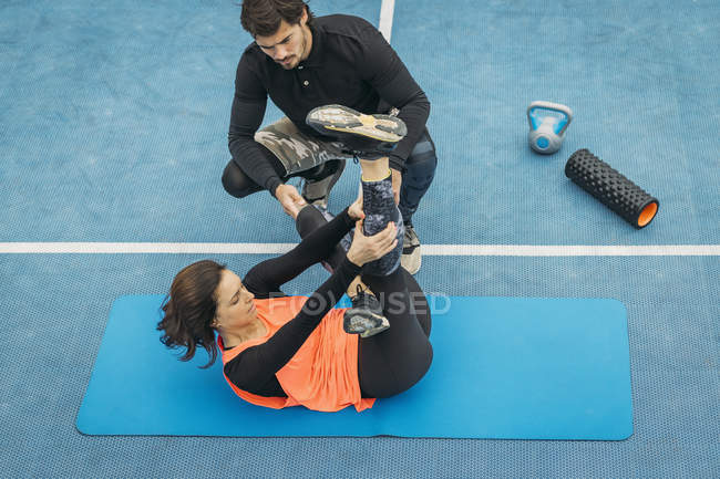 Fitte junge Frau macht Dehnübungen nach dem Training mit Personal Fitness Trainer. — Stockfoto