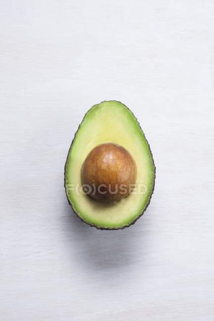 Авокадо розрізаний навпіл з каменем на білому тлі . — стокове фото