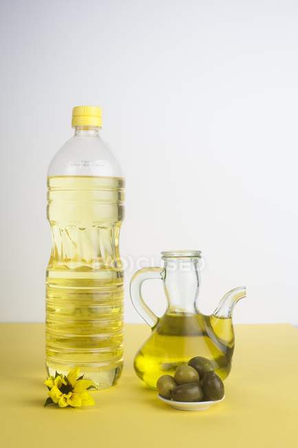 Botella de plástico de aceite de girasol y jarra de vidrio de aceite de oliva
. - foto de stock