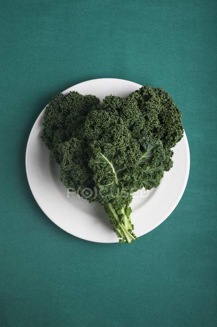 Feuilles de chou frisé en forme de coeur, Brassica oleracea, en plaque en forme de coeur . — Photo de stock