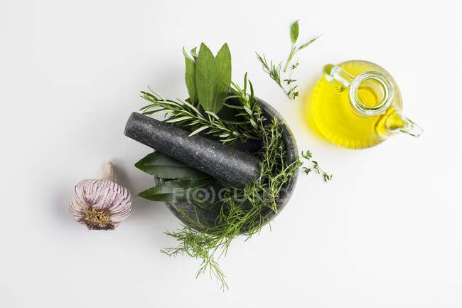 Mörser und Stößel mit Knoblauch und Kräutern und Olivenöl. — Stockfoto