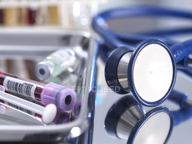 Nahaufnahme von Stethoskop neben Blutprobe im Reagenzglas, Spritze und medizinischem Fläschchen in einer Klinik. — Stockfoto