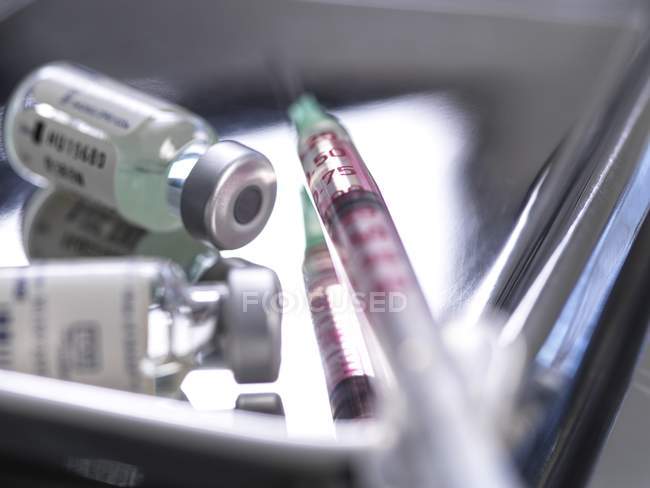 Vacuna en preparación en jeringa sobre bandeja metálica en clínica
. - foto de stock