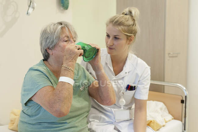 Hospital geriátrico. Enfermera ayudando a un paciente confuso en la sala geriátrica de un hospital. - foto de stock