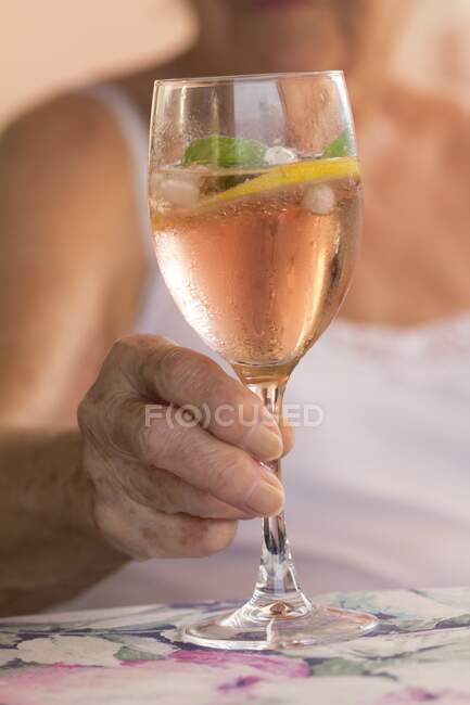 Close-up of elderly woman holding a glass of summer cocktail. — Stock Photo