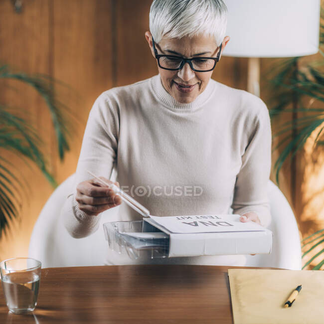 Senior woman doing a mailed DNA test at home. — Stock Photo