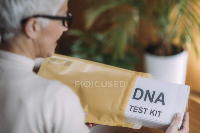Старша жінка робить поштовий тест ДНК вдома . — стокове фото