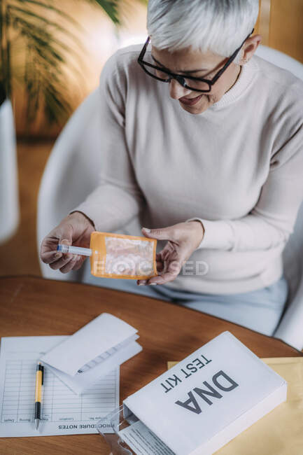 Femme âgée préparant le kit de test ADN. — Photo de stock