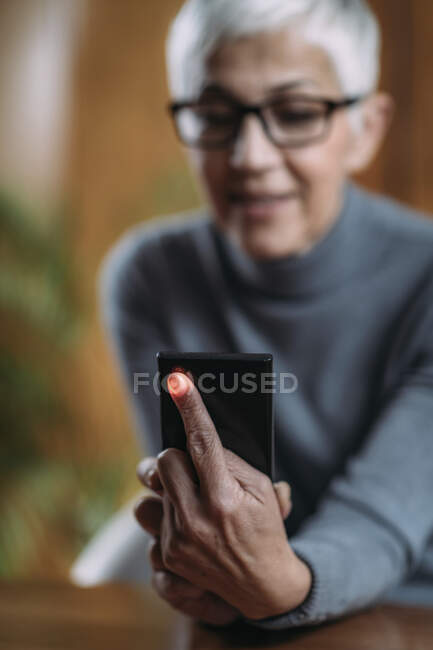Senior woman using smart phone app, measuring heart rate. — Stock Photo