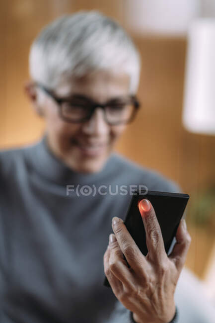 Seniorin misst Puls oder Herzfrequenz mit Smartphone. — Stockfoto
