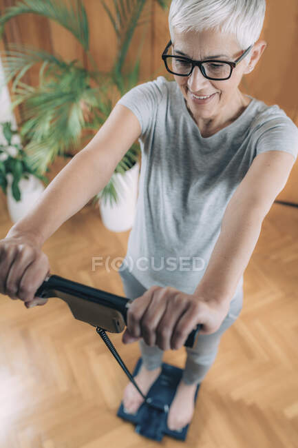 Healthy senior woman measuring body fat with body composition monitor. — Stock Photo