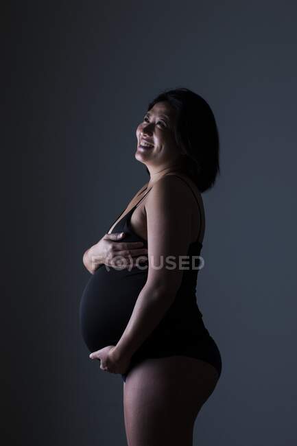 Vista lateral de la mujer embarazada feliz - foto de stock
