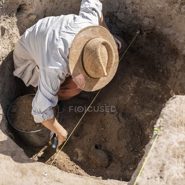 Arqueólogo desenterrando cerámica antigua en un sitio arqueológico. - foto de stock