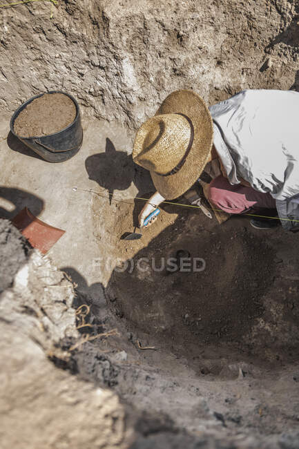 Archaeologist digging with hand trowel, recovering pottery from an archaeological site. — Fotografia de Stock