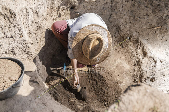 Arqueólogo excavando cerámica en un sitio arqueológico. - foto de stock